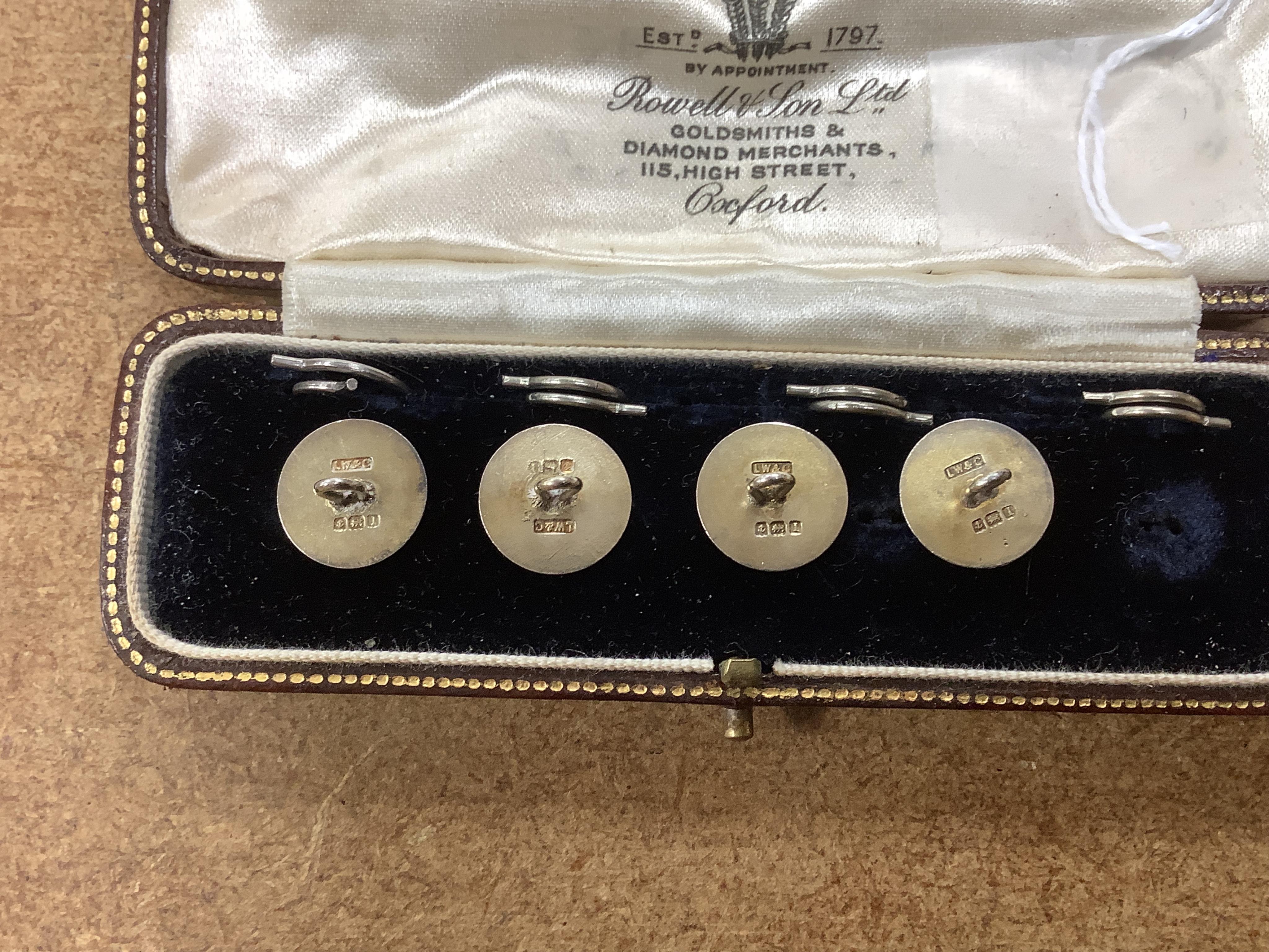 A set of four silver and two colour enamel buttons, by Lawson, Ward & Gammage Ltd, Birmingham, 1910, diameter 12mm, in original gilt tooled leather case by Rowell & Son Ltd of Oxford.